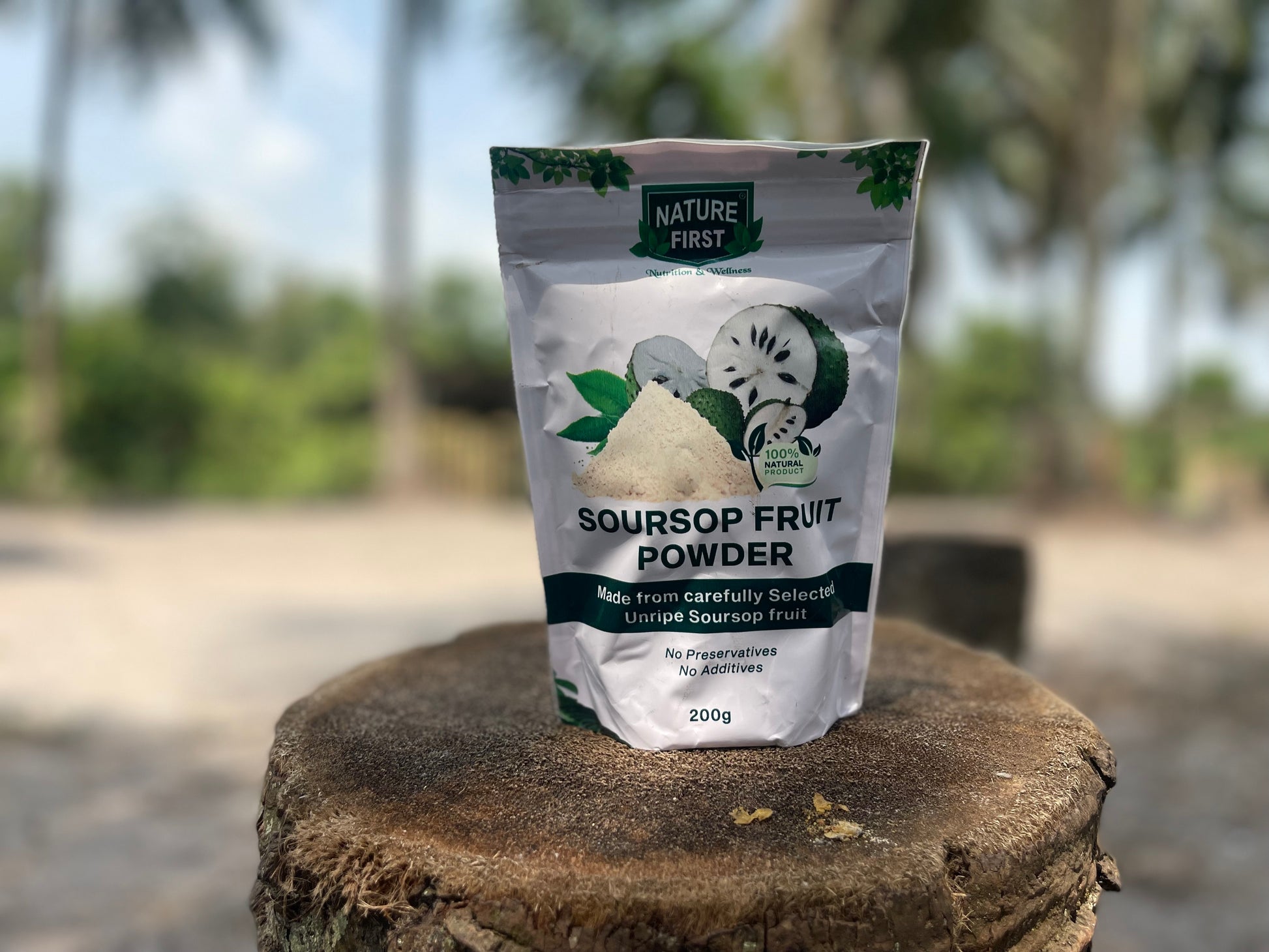 Package of Nature First Soursop Fruit Powder on a wooden stump with a blurred natural background