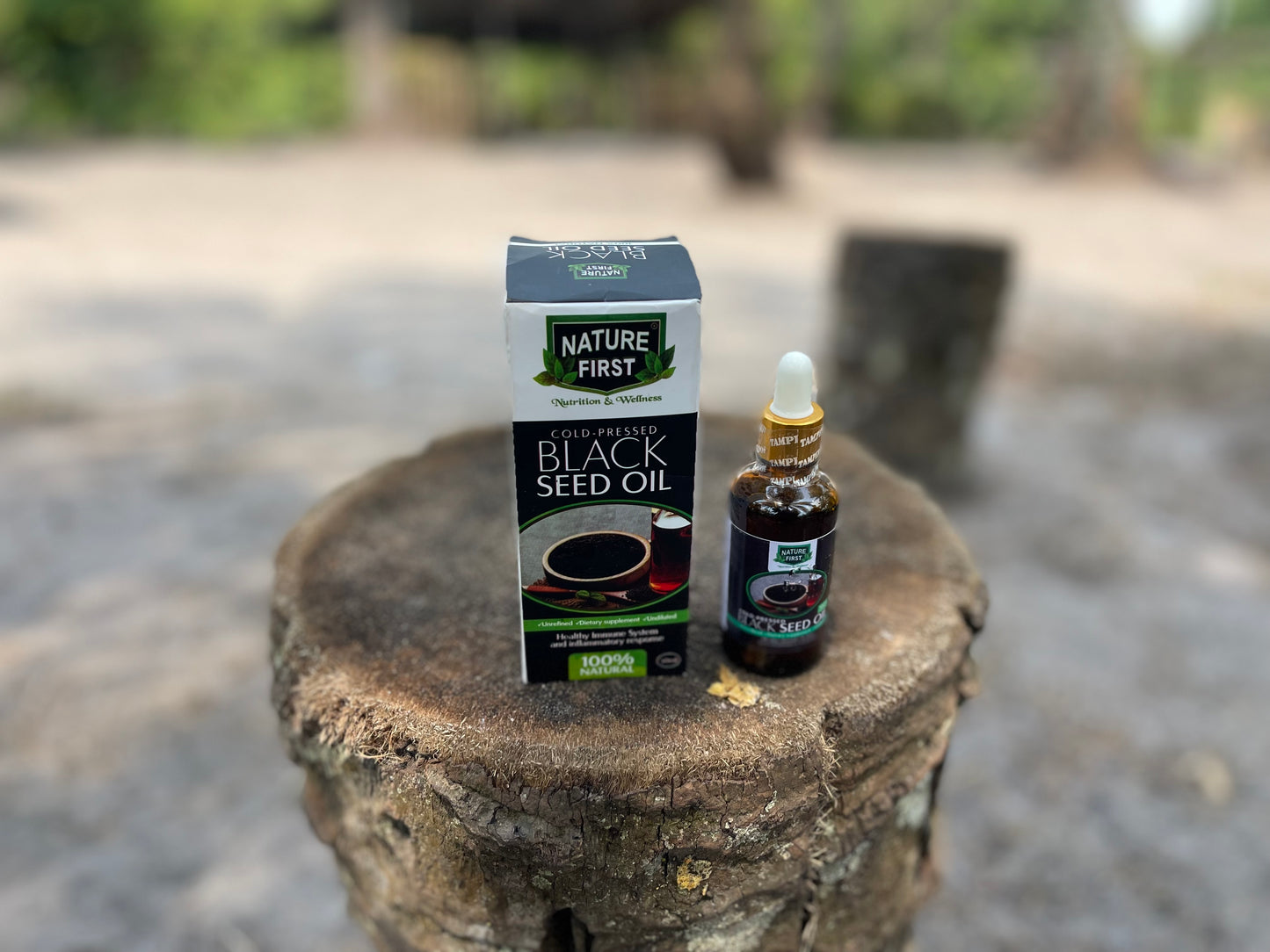 Nature First Black Seed Oil packaging and bottle on a stone surface with a blurred outdoor background